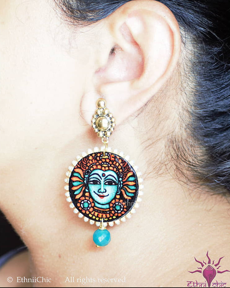 Close-up of a woman wearing the Kerala Mural Hand-Painted Earrings – Krishna Teal 