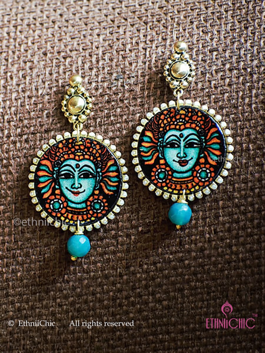 Pair of Kerala Mural Hand-Painted Earrings – Krishna Teal small on a brown fabric background