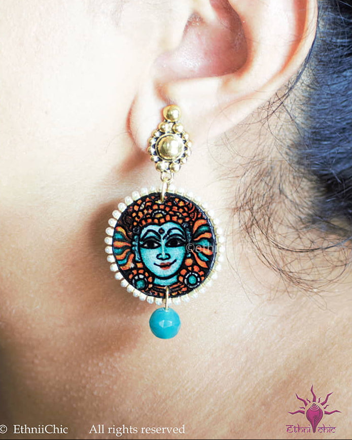 Close-up of a woman wearing the Kerala Mural Hand-Painted Earrings – Krishna Teal Small